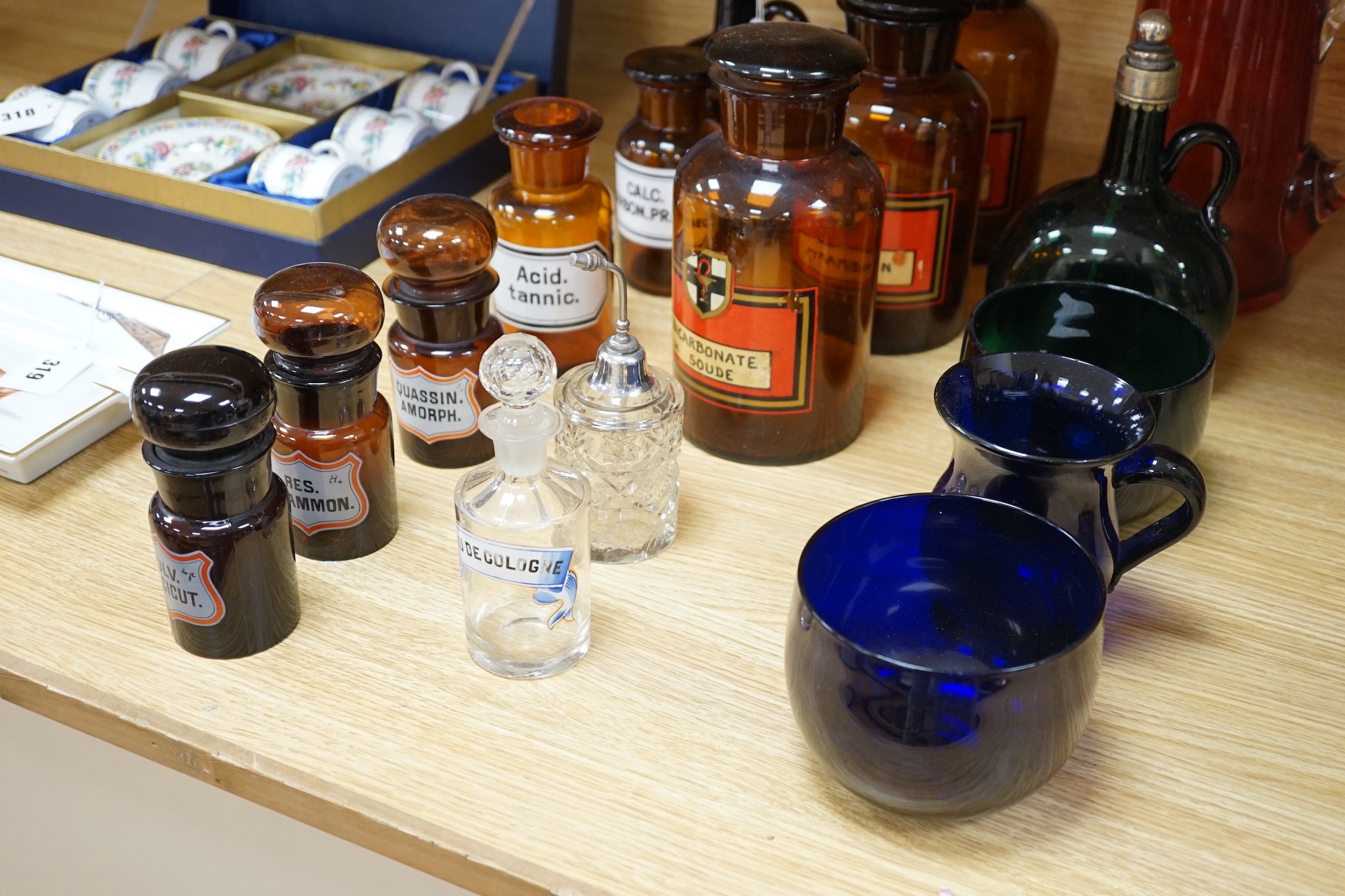Nine glass chemist jars and covers, two decanters, two rinsers, and a cranberry jug and a mug, mostly coloured glass, jug 21 cams high